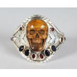 A SILVER CARVED TIGERS EYE AND GARNET SET SKULL BRACELET.