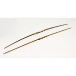 TWO EARLY LONG BOWS, bound leather and fibre grip. Longest: 6ft 2ins (2).