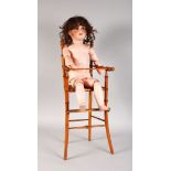 A TALKING DOLL, UNIS FRANCE, No. 301, in a CHILD'S BAMBOO HIGH CHAIR.