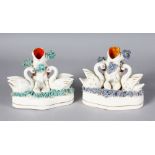 A PAIR OF STAFFORDSHIRE SWAN SPILL VASES, two swans with two cygnets, on shaped, encrusted bases.