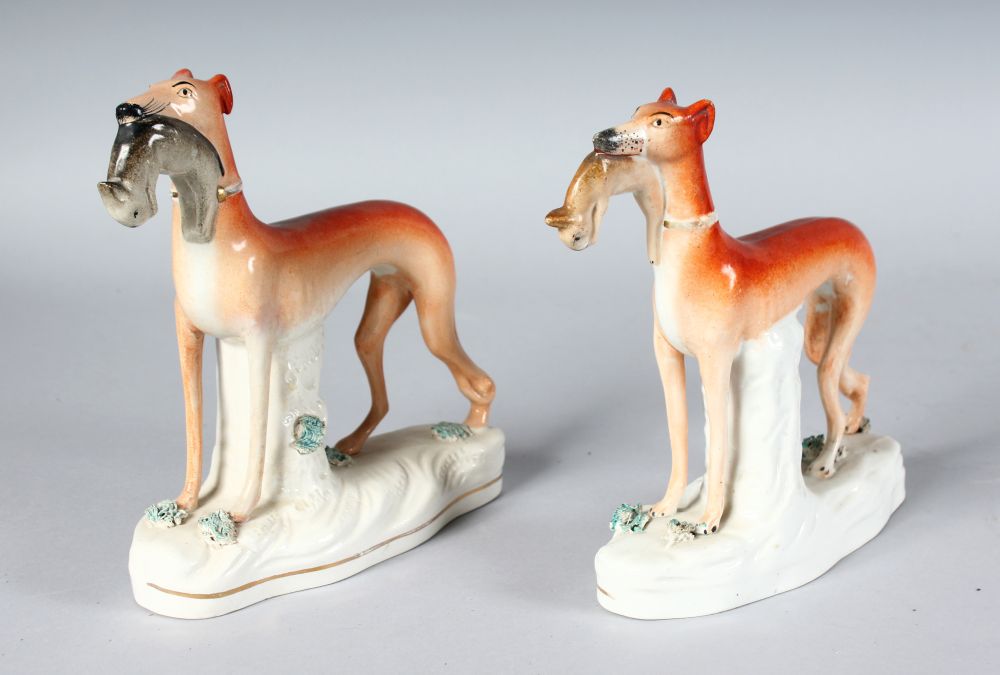A PAIR OF STAFFORDSHIRE STANDING WHIPPETS with rabbits in their mouths, on waisted, encrusted,