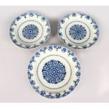 A SET OF THREE 18TH CENTURY BLUE AND WHITE DELFT CIRCULAR CHARGERS with scalloped edges. 15ins and