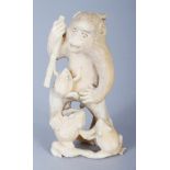 A JAPANESE MEIJI PERIOD IVORY OKIMONO OF AN ANIMATED MONKEY, holding a bamboo flute and in the