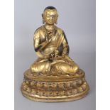 A SINO-TIBETAN GILT BRONZE FIGURE OF A LAMA, seated in dhyanasana of a double lotus plinth, the