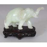 A CHINESE CELADON GREEN BOWENITE CARVING OF A STRIDING ELEPHANT, together with a fitted wood