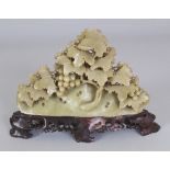 A 20TH CENTURY CHINESE CELADON GREEN SOAPSTONE CARVING OF FRUITING VINE, on a separate brown