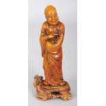 A CHINESE SHOUSHAN STONE FIGURE OF A STANDING SAGE, together with a fitted soapstone stand, 5.5in