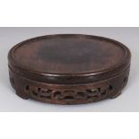 A CHINESE CIRCULAR WOOD VASE STAND, the sides carved and pierced with scroll work, 7.6in diameter,