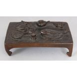 A SMALL JAPANESE BRONZE MODEL OF A LOW TABLE, its top surface cast with a tetsubin and a variety