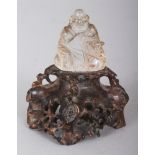 A SMALL CHINESE ROCK CRYSTAL FIGURE OF BUDAI, together with a fixed carved soapstone stand, 4in high