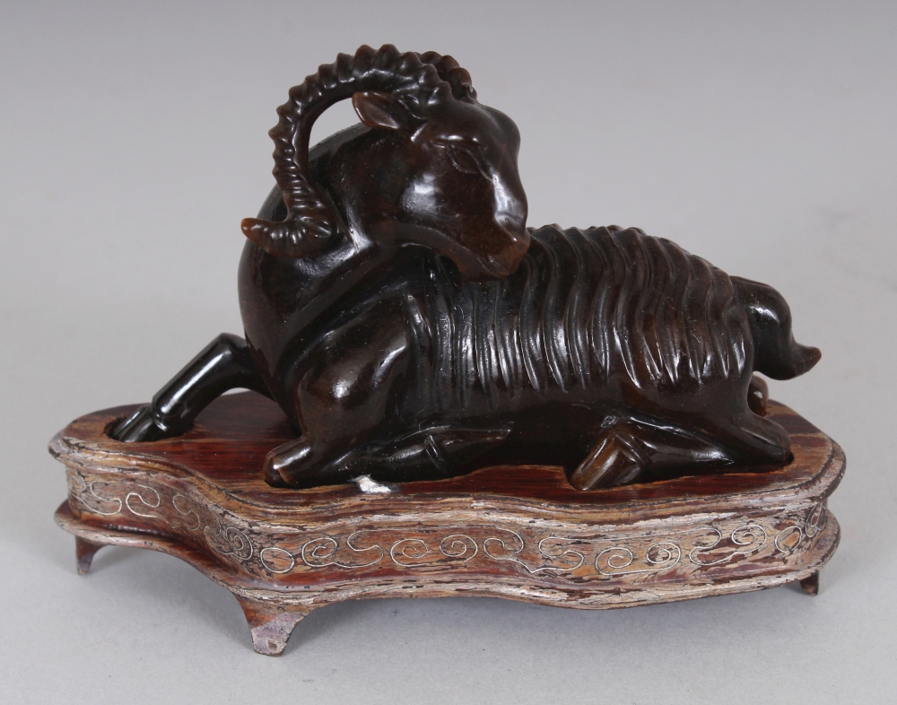 A CHINESE TIGER’S EYE STONE MODEL OF A RAM, together with a fitted wire-inlaid wood stand, 2.75in