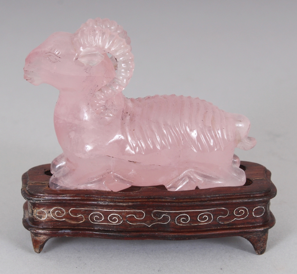 A CHINESE ROSE QUARTZ MODEL OF A RAM, together with a fitted wire-inlaid wood stand, 2.75in high