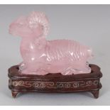 A CHINESE ROSE QUARTZ MODEL OF A RAM, together with a fitted wire-inlaid wood stand, 2.75in high