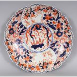 AN EARLY 20TH CENTURY JAPANESE IMARI PORCELAIN DISH, with a shaped rim, 12in diameter.
