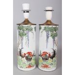 A MIRROR PAIR OF EARLY 20TH CENTURY CHINESE CYLINDRICAL PORCELAIN VASES, fitted for electricity,