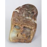 A CHINESE BROWN JADE BOULDER, carved in deep relief with a river boat beneath pine and beneath a