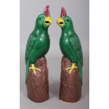 A MIRROR PAIR OF EARLY 20TH CENTURY CHINESE PORCELAIN MODELS OF PARROTS, each base unglazed, 10.