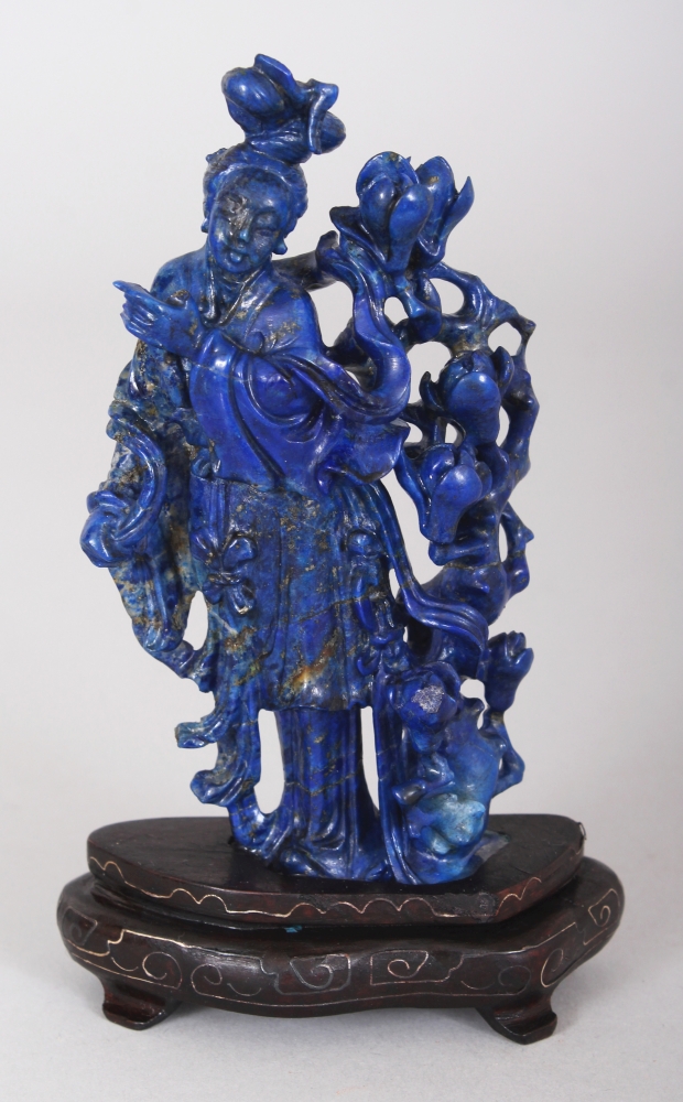 A CHINESE LAPIS CARVING OF GUANYIN, together with a wire-inlaid fixed wood stand, 5.25in high