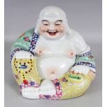 A 20TH CENTURY CHINESE FAMILLE ROSE PORCELAIN FIGURE OF BUDAI, seated in patterned robes with