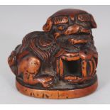 A JAPANESE MEIJI PERIOD CARVED WOOD NETSUKE OF A SHI-SHI, its chin resting on a brocaded ball, 1.