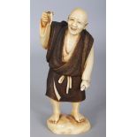 A FINE QUALITY SIGNED JAPANESE MEIJI PERIOD STAINED IVORY OKIMONO OF A CHEERFUL MAN, holding aloft a