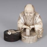 A SIGNED JAPANESE MEIJI PERIOD SECTIONAL IVORY & WOOD OKIMONO OF A SEATED ARTISAN, holding a chisel,