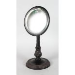 A CEYLONESE CARVED EBONY MIRROR, on a circular base. 13ins high.