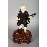 A GOOD JAPANESE BRONZE AND IVORY FIGURE OF A MAN playing a musical instrument, standing on a