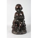 A LARGE CARVED WOOD SEATED CHERUB. 23ins high.