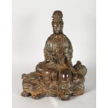 A CHINESE BRONZE GUANYIN KWAN-YIN BUDDHA RIDING A FOO DOG, dark patina stamp to the base. 10.5ins