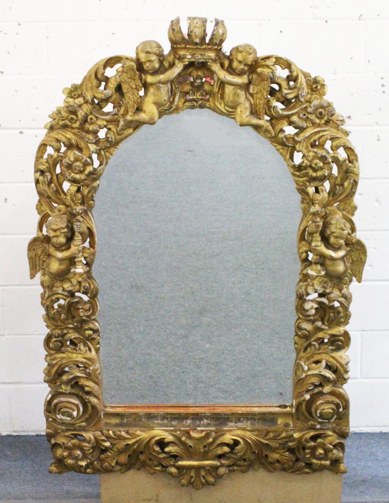 A GOOD 18TH CENTURY ITALIAN CARVED AND GILDED MIRROR, the frame carved with four winged cupids,