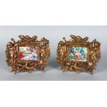 A PAIR OF PORCELAIN PANELS, 2ins x 2.5ins, in a gilt metal cupid easel frames.