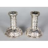 A GOOD PAIR OF VICTORIAN CIRCULAR CANDLESTICKS, with repousse scrolls. 4.5ins high. Victorian London