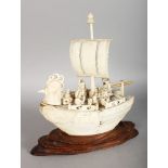 A GOOD JAPANESE CARVED IVORY BOAT ON STAND with sail, seven various figures. 8ins long.