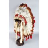 A RED INDIAN HEADDRESS, bears label McCUE BROS. & DRUMMOND, NEW YORK, on a wooden stand.
