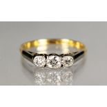 AN 18CT GOLD AND DIAMOND THREE STONE RING.