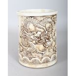 A CHINESE WHITE PORCELAIN BRUSH POT, with dragon decoration. 5.5ins.