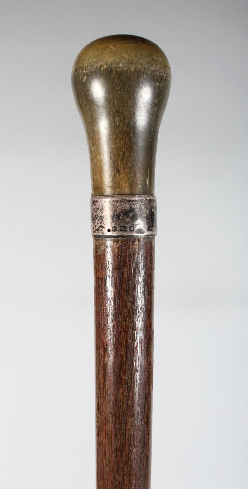 ANOTHER RHINO HORN HANDLED WOOD CANE, with a plain hallmarked silver collar, the shaped rhinoceros