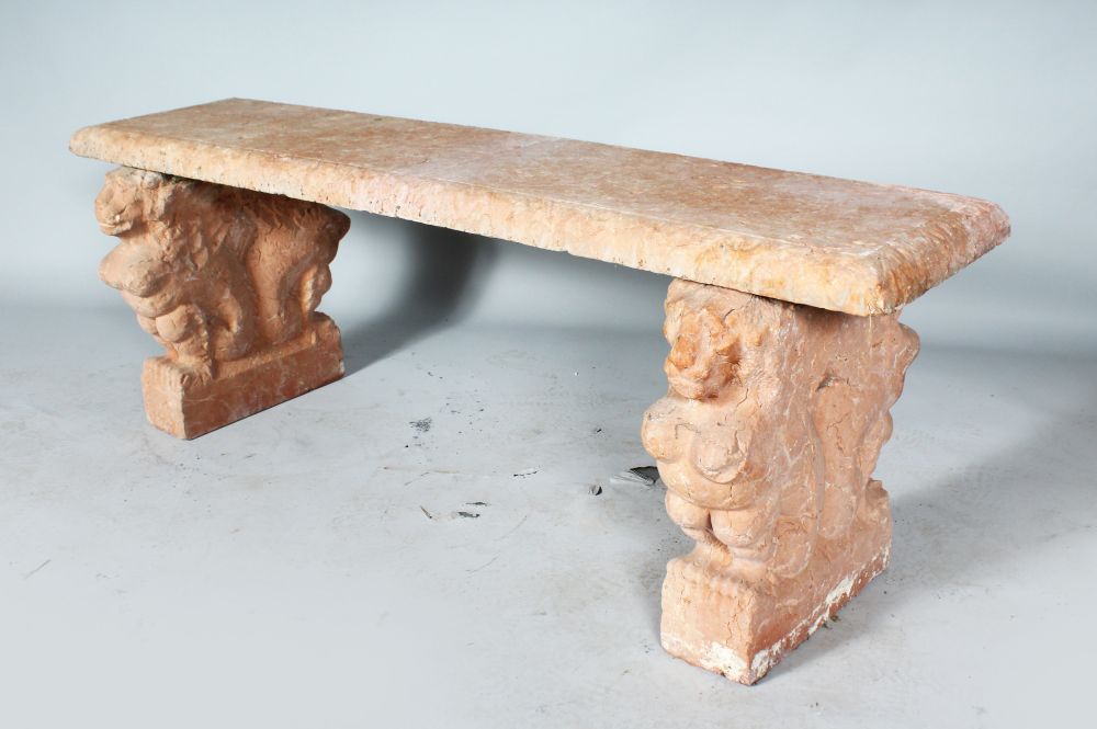 A CARVED RED STONE SEAT with lion supports. 4ft 4ins long.