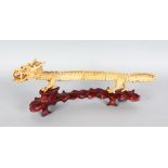 A LONG CHINESE IVORY ARTICULATED DRAGON on a wooden stand. 15ins long.
