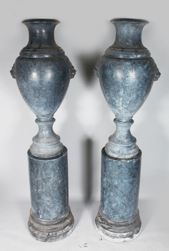 A LARGE PAIR OF CLASSICAL MARBLED URNS ON STANDS with lion masks. 7ft high.