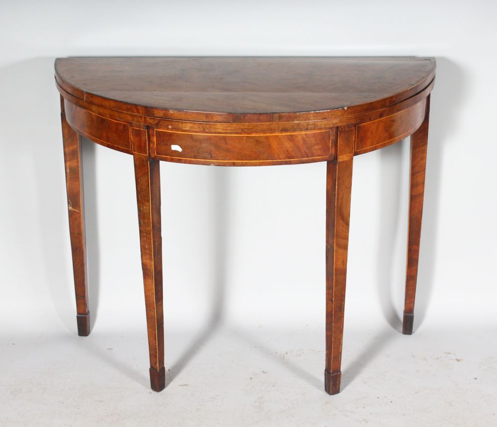 A GEORGE III FIGURED MAHOGANY HALF MOON CARD TABLE, with fold-over top, green baize interior,