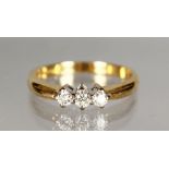 AN 18CT GOLD AND DIAMOND THREE STONE RING.