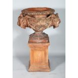 A GOOD TERRACOTTA CIRCULAR URN ON STAND, with rams masks and oak leaves. 2ft diameter x 3ft high.