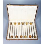 A SET OF TWELVE SILVER GILT LONG HANDLED SPOONS with shell bowls. Stamped .800, in a good leather