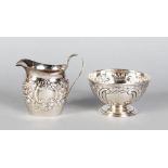 A SMALL VICTORIAN MILK JUG AND SUGAR BASIN, with repousse decoration. London 1896 and Chester 1900.