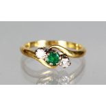 AN 18CT GOLD, DIAMOND AND EMERALD CROSSOVER RING.