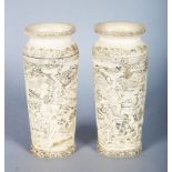 A GOOD PAIR OF JAPANESE CARVED IVORY VASES, carved with many figures. 5.5ins high.