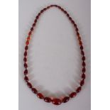 AN AMBER NECKLACE, weighing approx. 80.5gm, composed of graduated oval beads, the smallest bead 0.