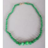 AN APPLE GREEN JADE-LIKE HARDSTONE NECKLACE, composed of graduated spherical beads, the largest bead